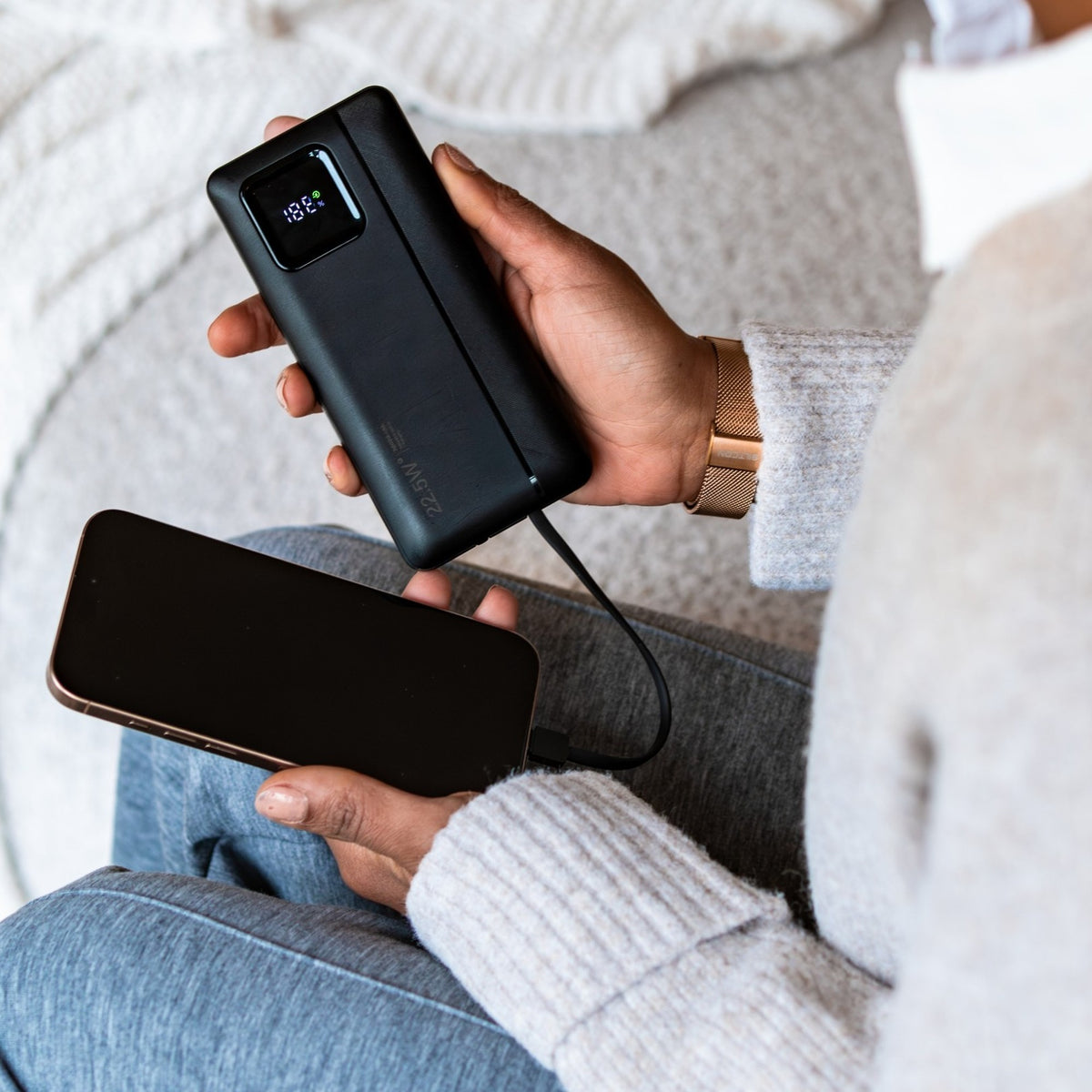 Vrouw op de bank laadt haar telefoon op met de Siltcon powerbank