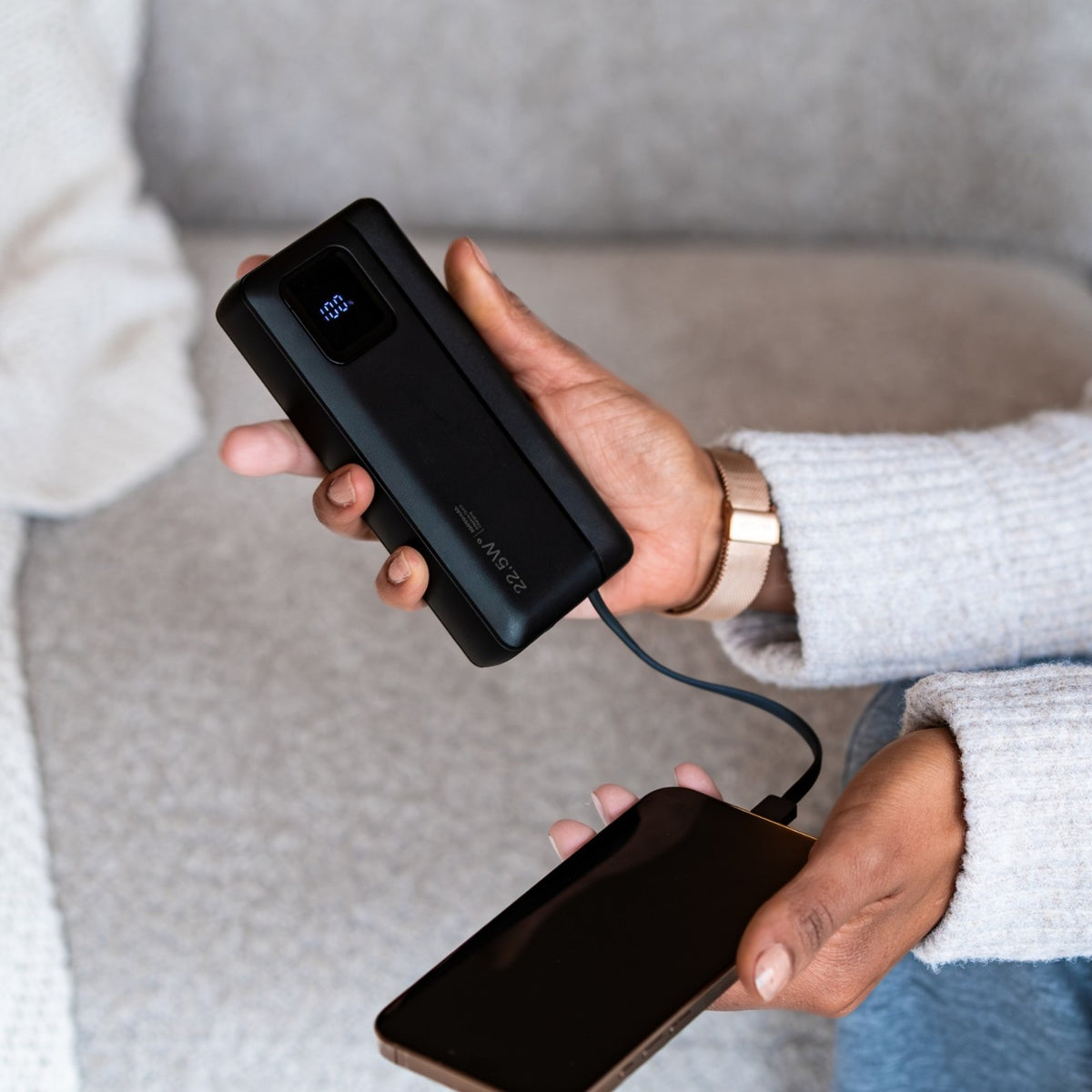Powerbank in de hand, telefoon aangesloten via de ingebouwde kabel